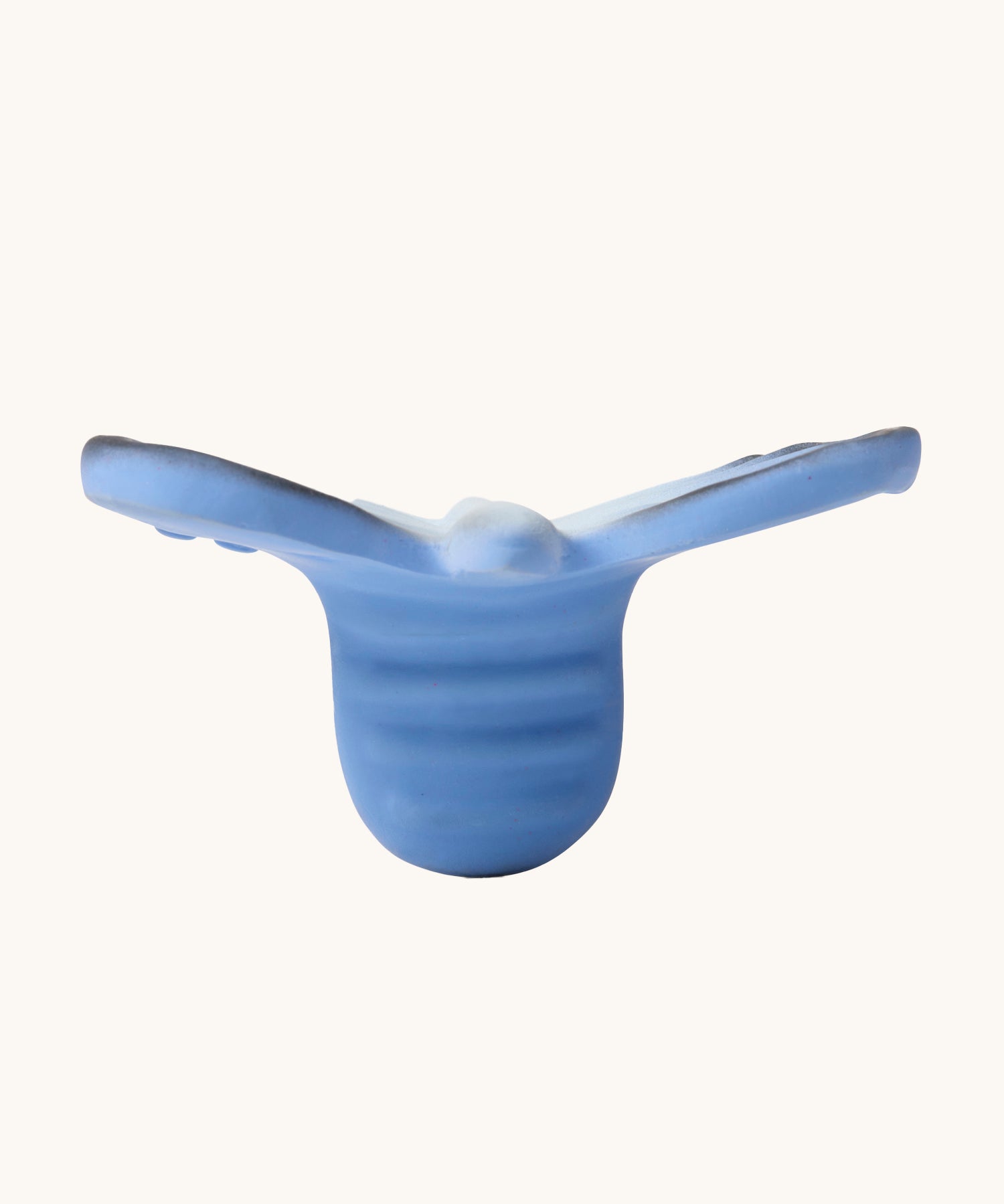 A side view of the Oli & Carol Natural Rubber Mini Teether - Blues The Butterfly, showing the texture of the teether, on a cream background