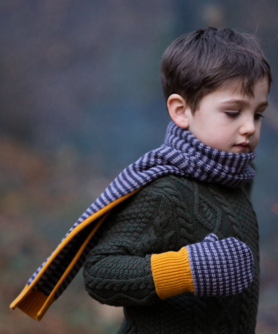 A child outside wearing the LGR lovely Dreamy Blue Stripe scarf and mittens