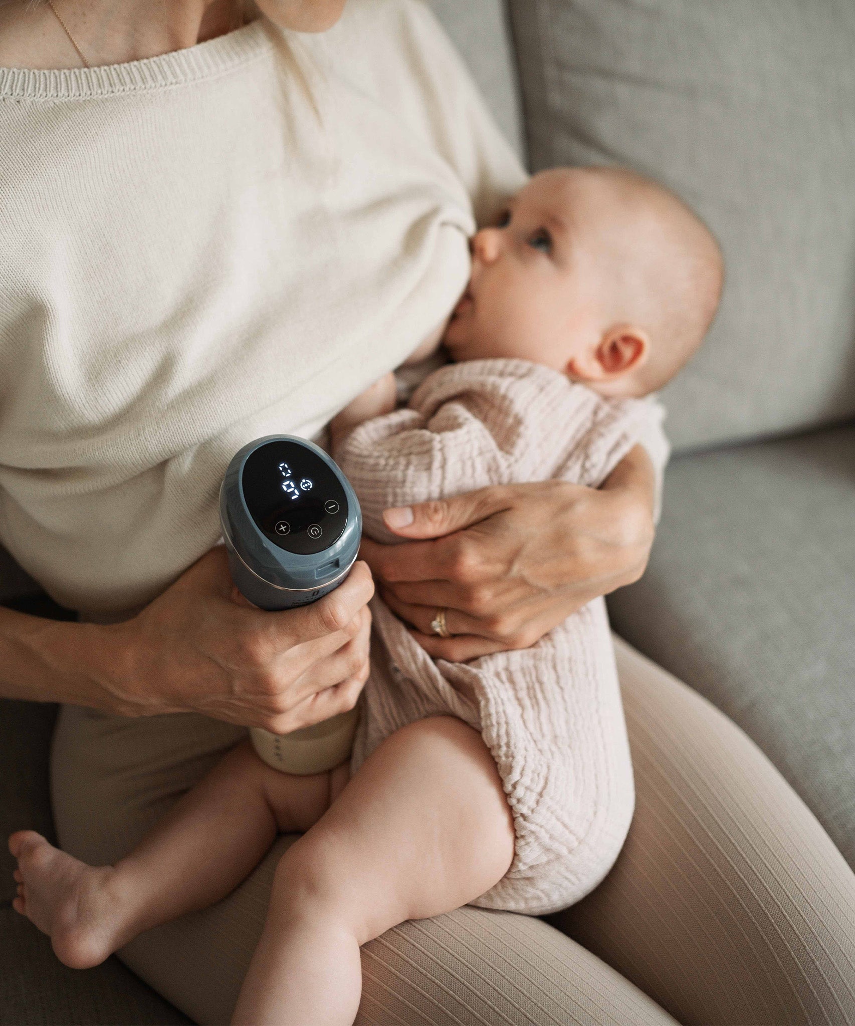 A person breastfeeding their child and using the Lola&Lykke Smart Electric Breast Pump at the same time. 