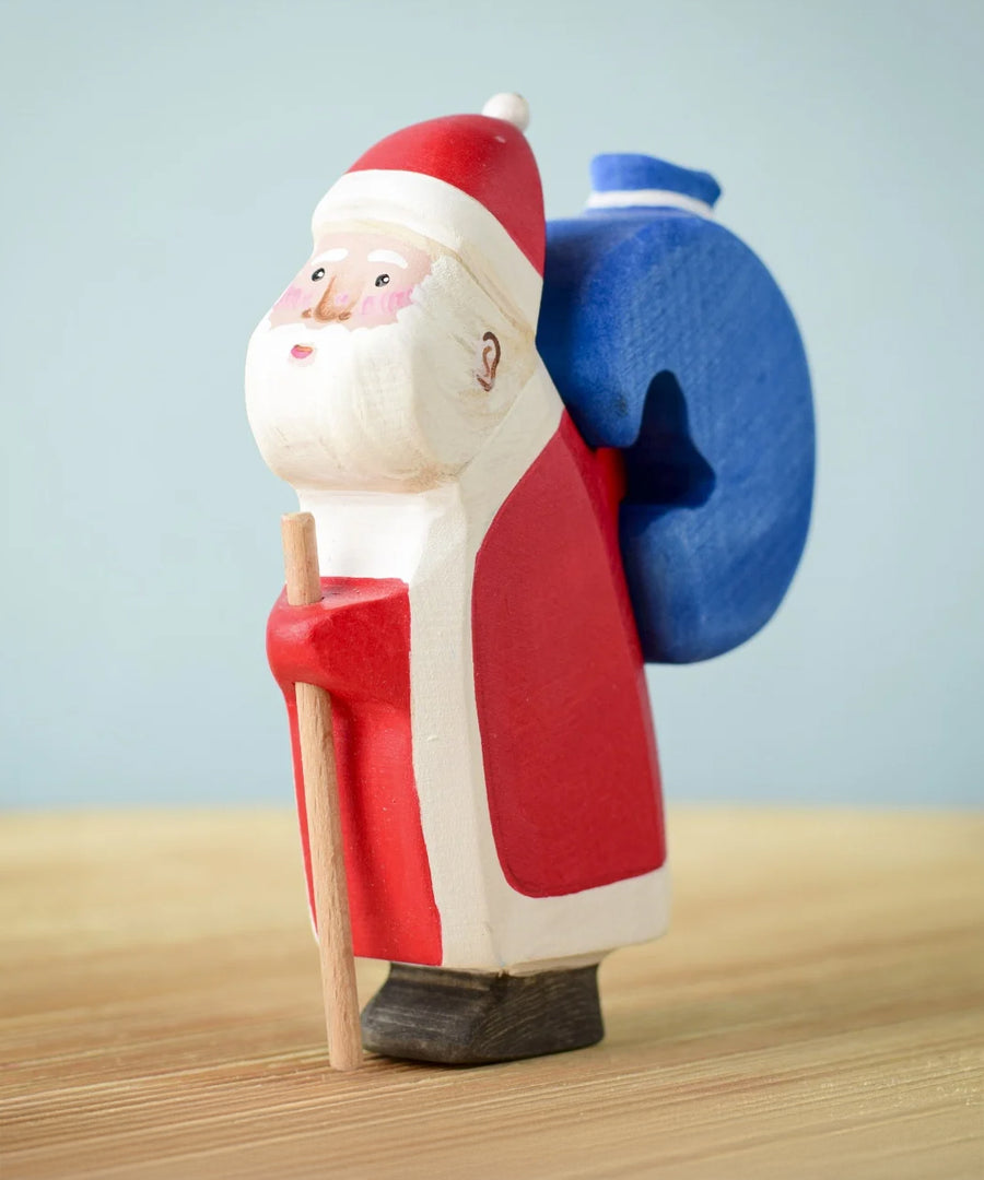 The Bumbu hand crafted and hand painted Santa figure on a light blue and light brown background