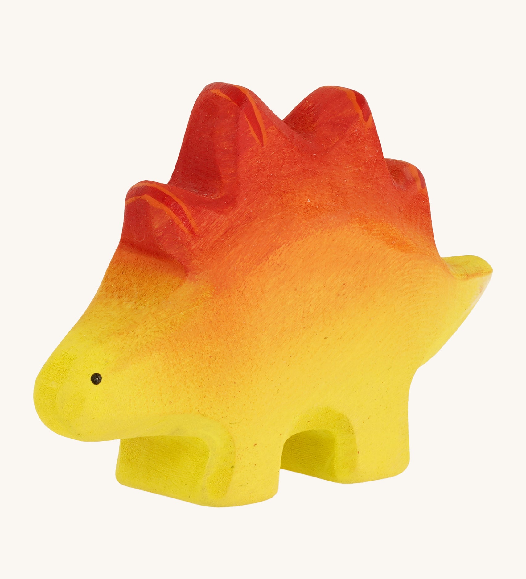 Bumbo wooden baby stegosaurus toy figure on a plain background