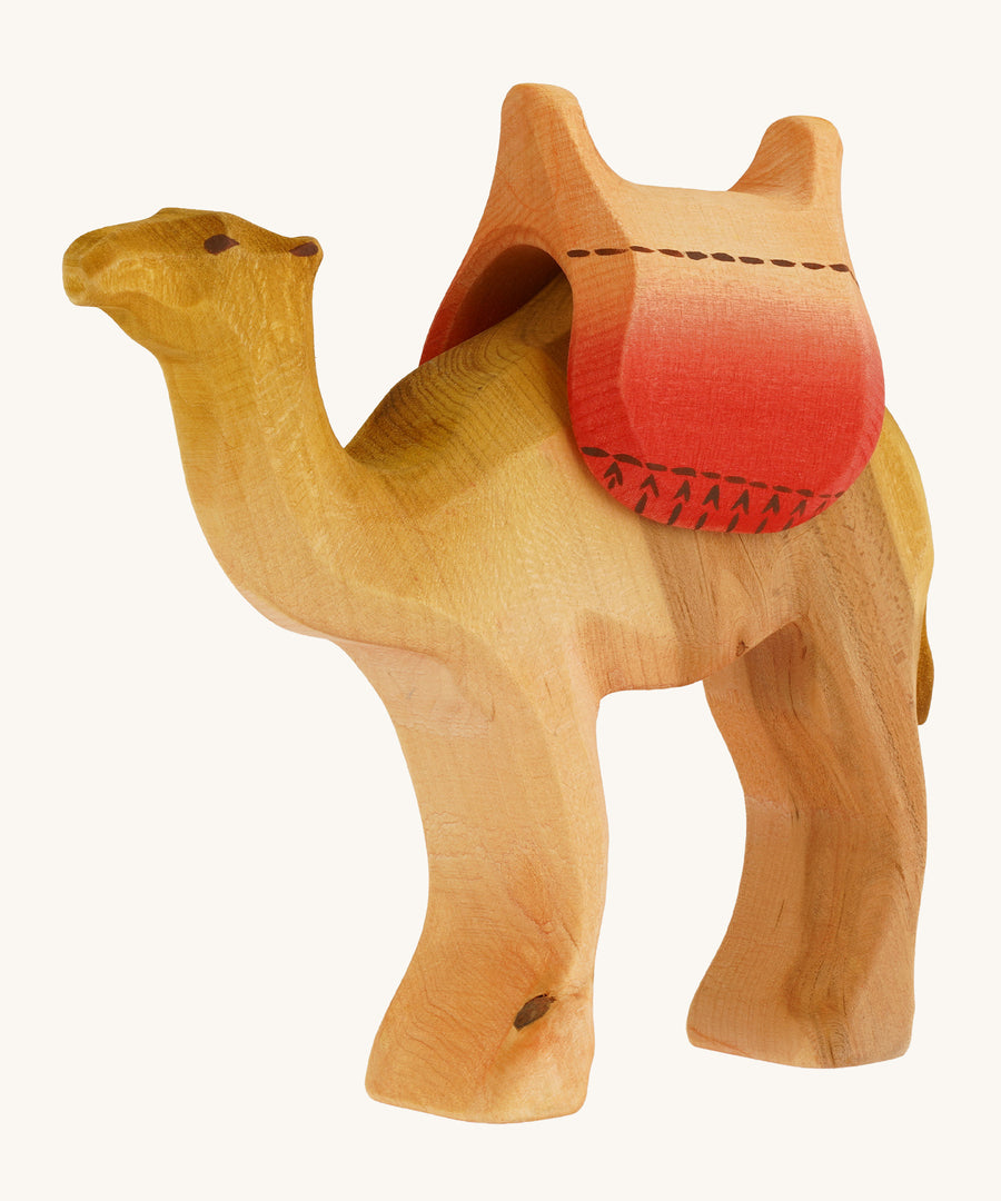 Bumbu wooden camel figure with saddle on a plain background.