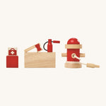 The wooden figures included in the PlanToys Fire Station, a first aid bag, an axe, a fire extinguisher and a fire hydrant on a cream background