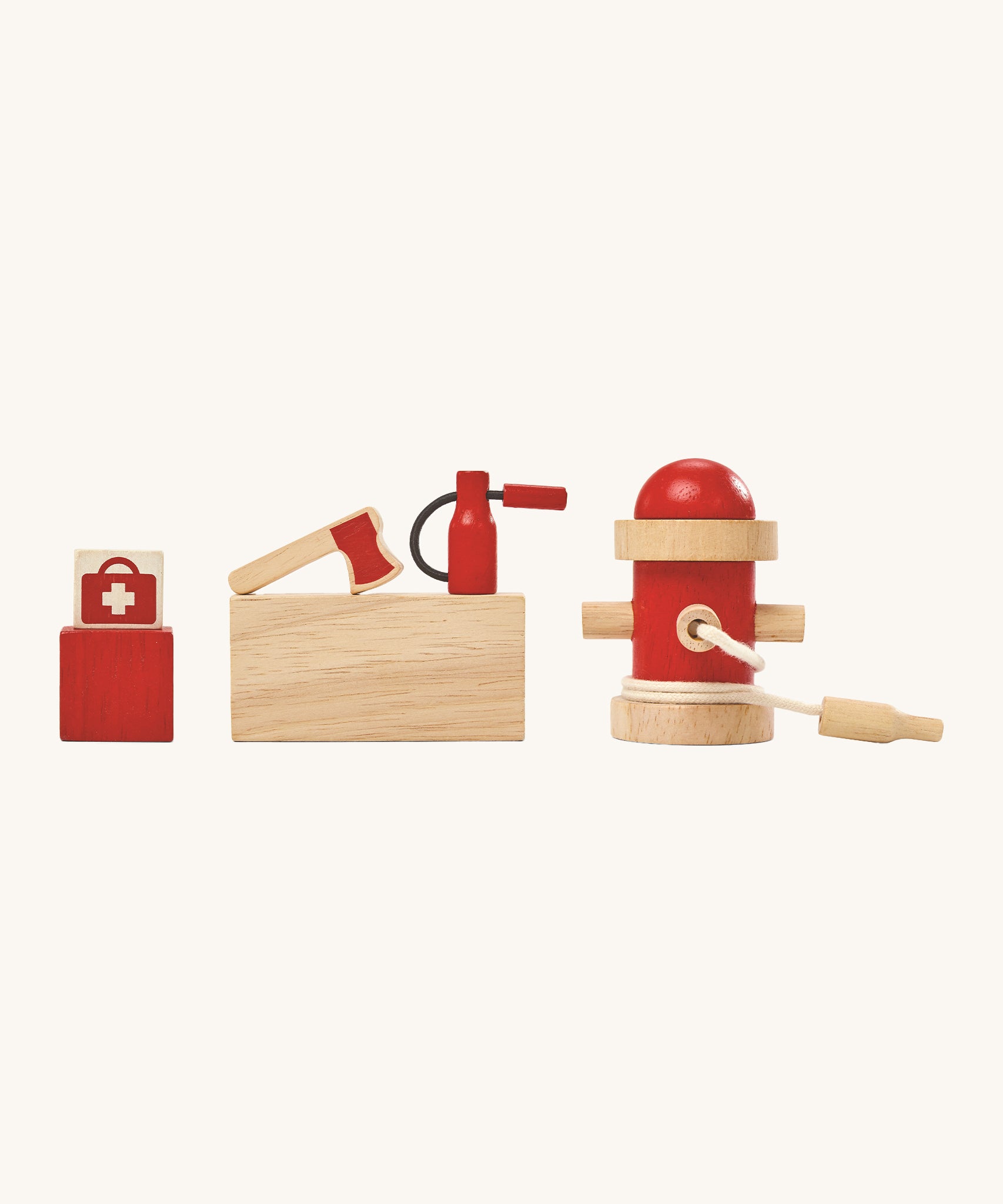 The wooden figures included in the PlanToys Fire Station, a first aid bag, an axe, a fire extinguisher and a fire hydrant on a cream background