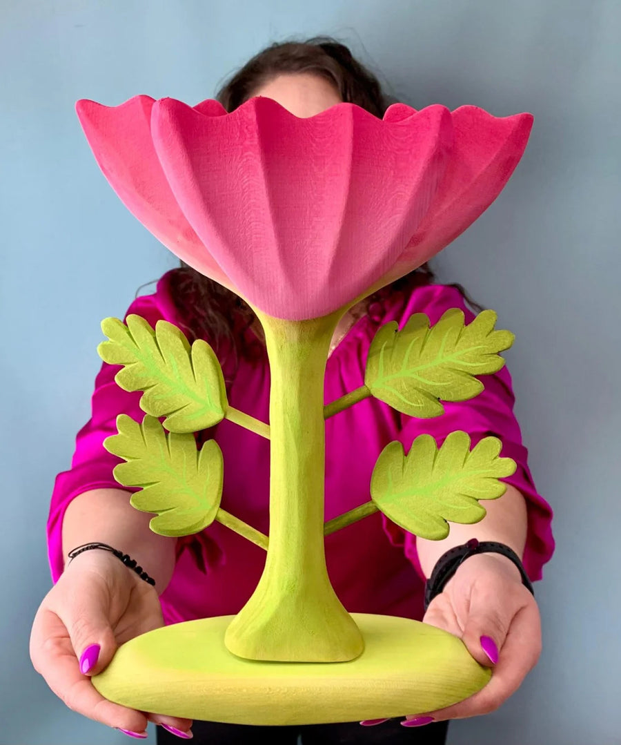 A person holding up the Bumbu Wooden Large Pink Flower in front of them.