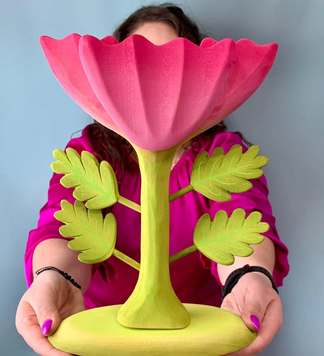 A person holding up the Bumbu Wooden Large Pink Flower in front of them.