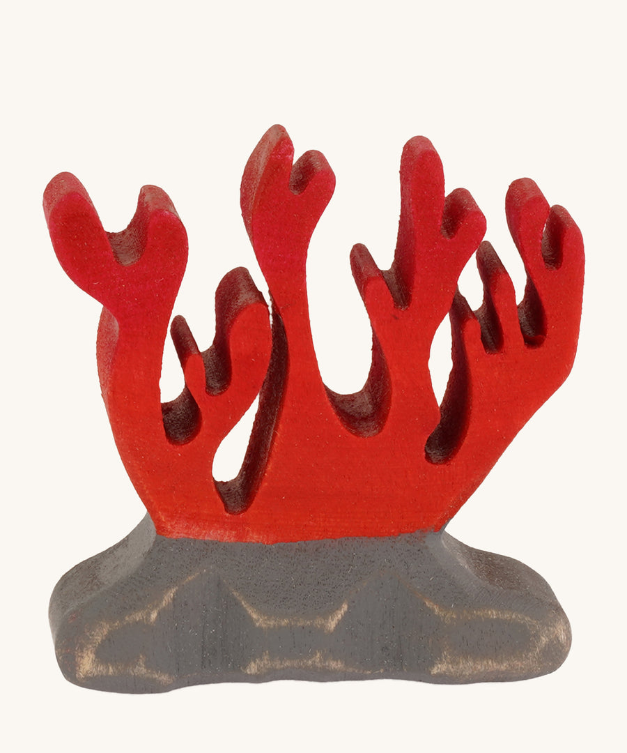 Bumbu wooden red coral toy figure on a plain background.