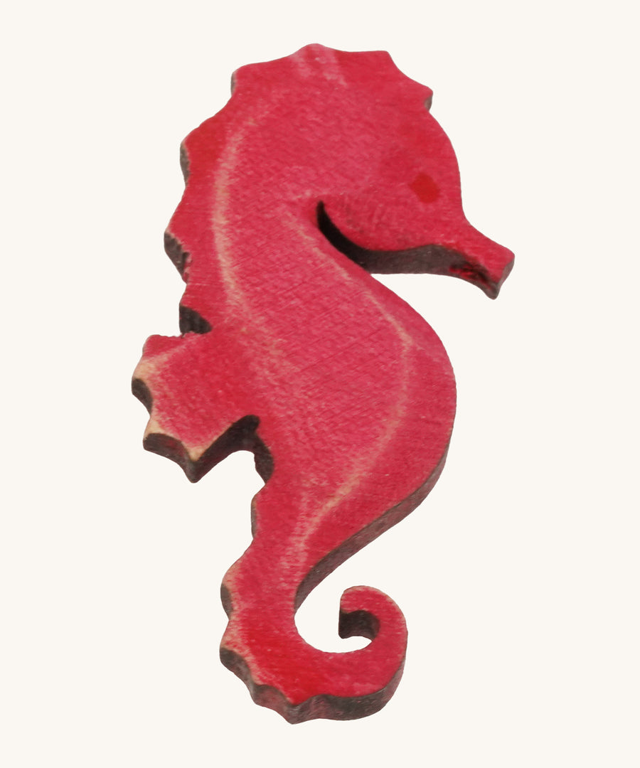 Bumbu pink wooden seahorse figure on a plain background.