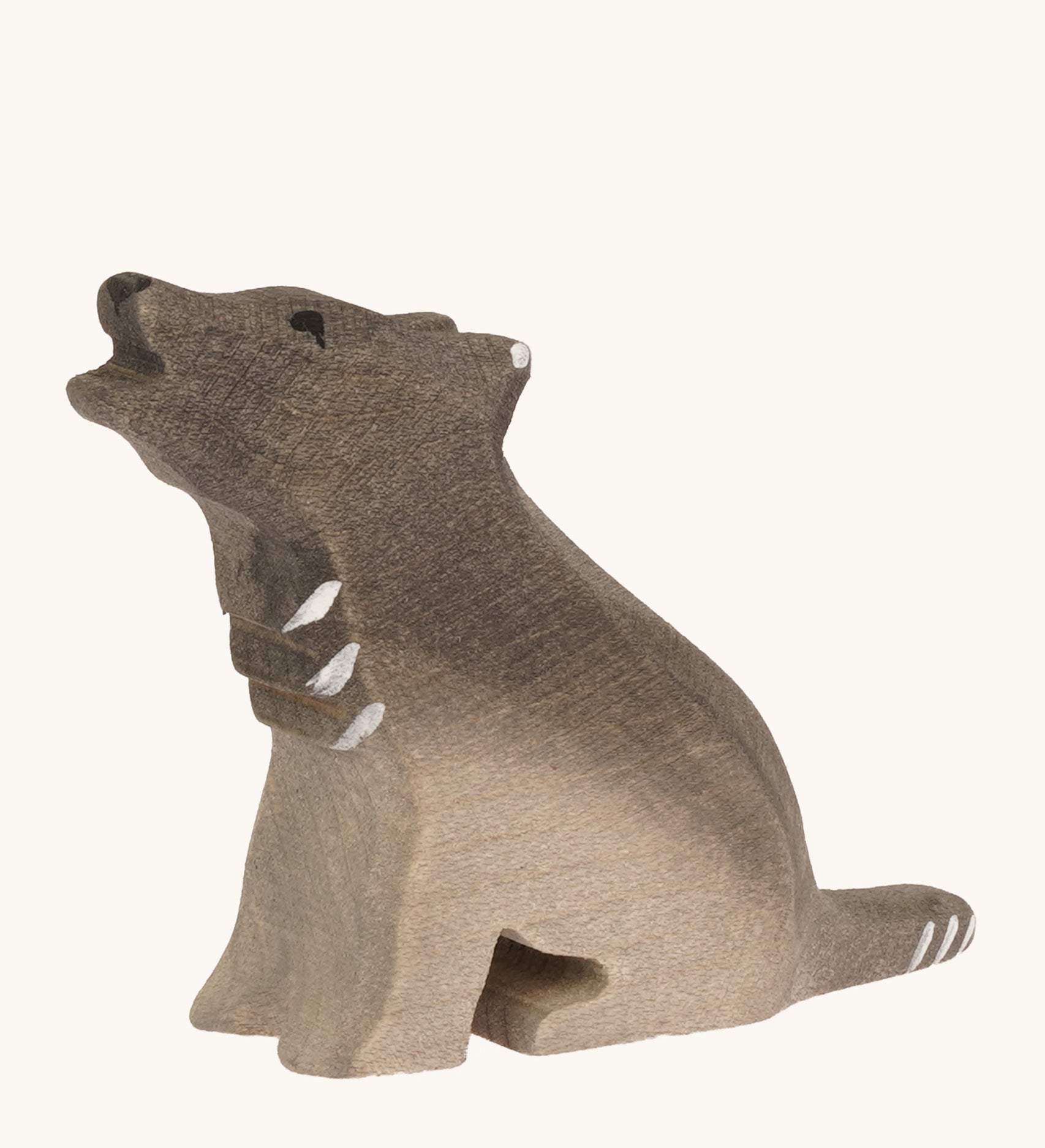 A Bumbu small wooden sitting wolf cub on a plain background.