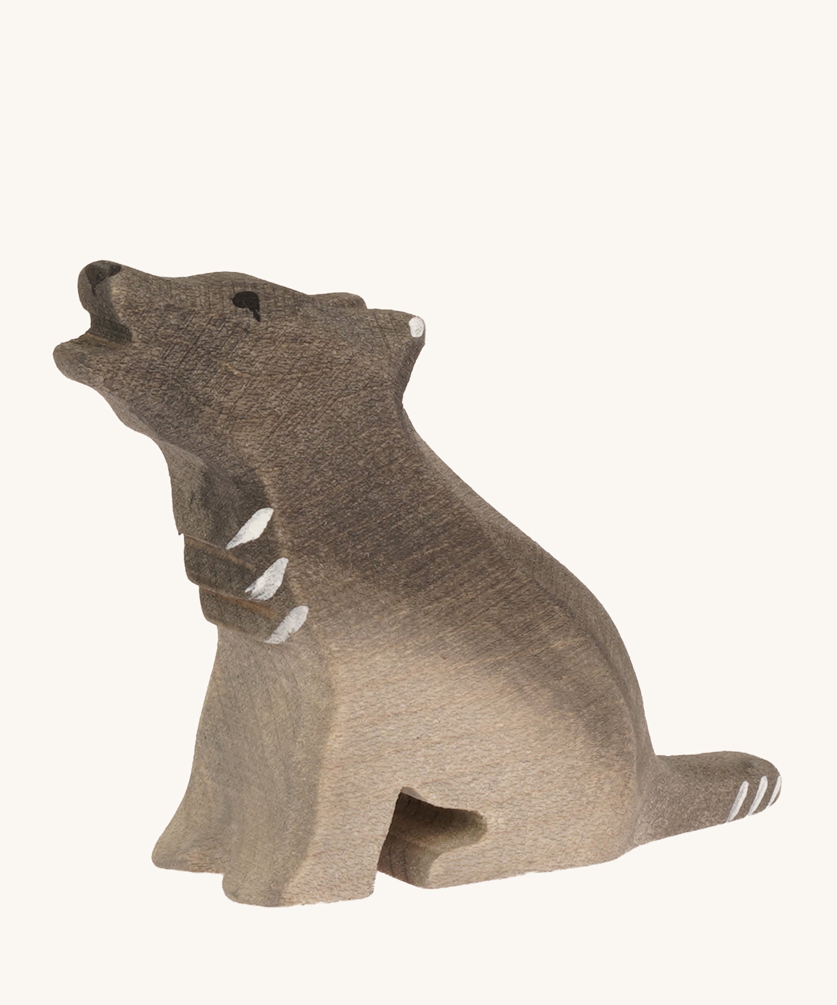 A Bumbu small wooden sitting wolf cub on a plain background.