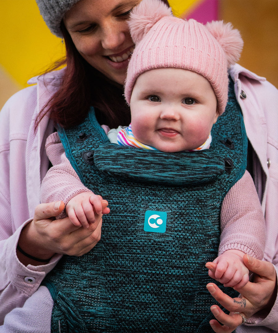 A child facing outwards in the multi-positional Carifit+ Baby Carrier in Cool Green