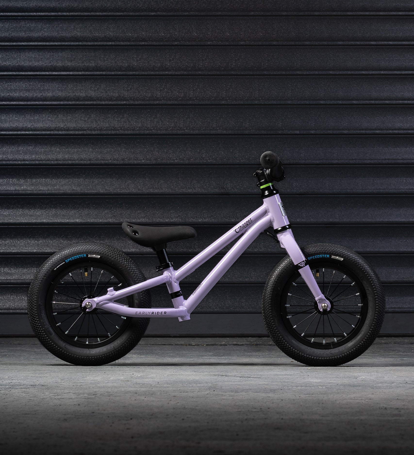 A side on view of the Early Rider Charger Balance Bike - Violet Haze, on a grey background