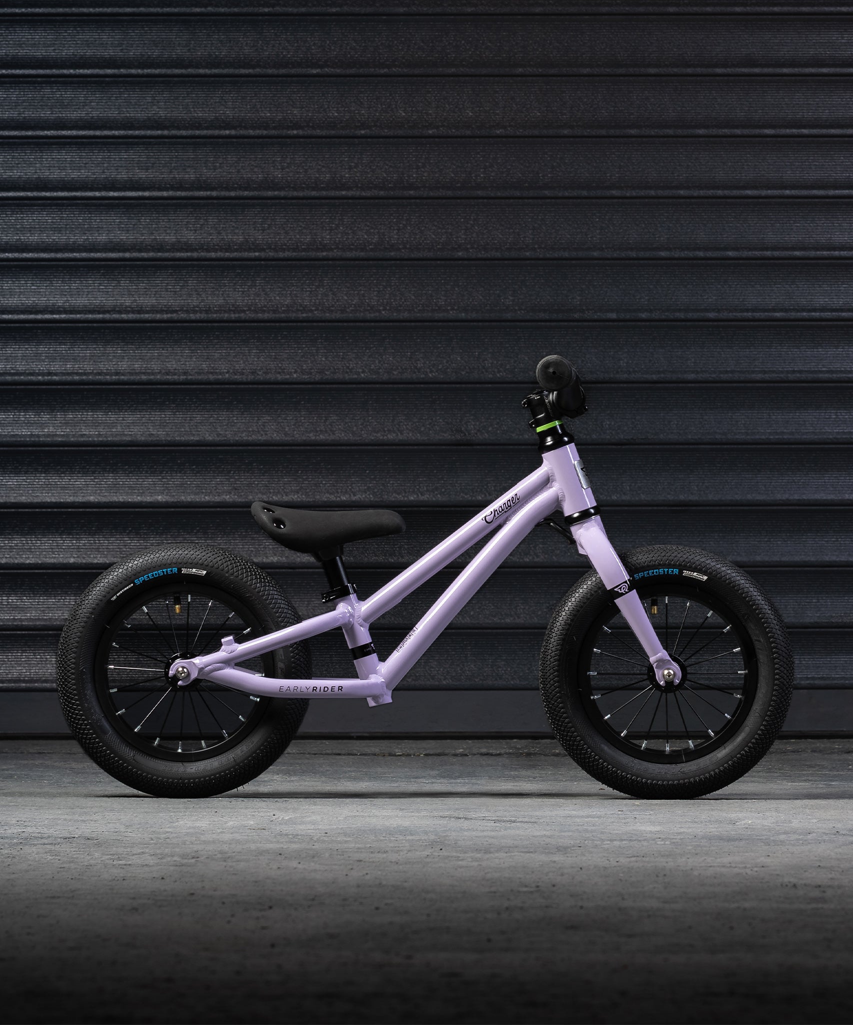 A side on view of the Early Rider Charger Balance Bike - Violet Haze, on a grey background