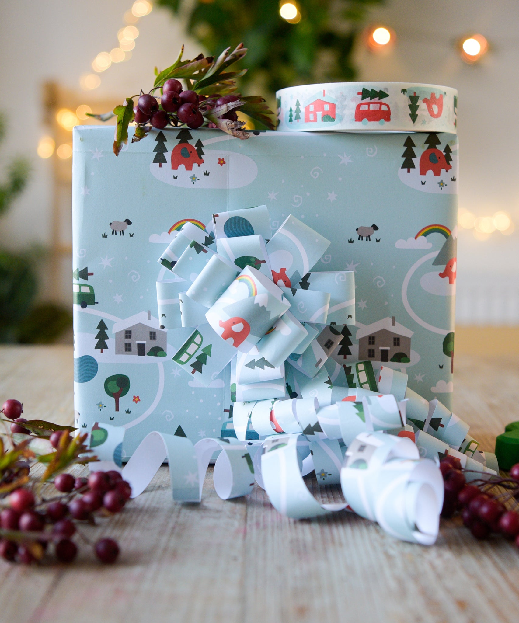 A box on a table wrapped in Babipur Christmas paper. There's a roll of babipur Christmas paper tape on top of the box.