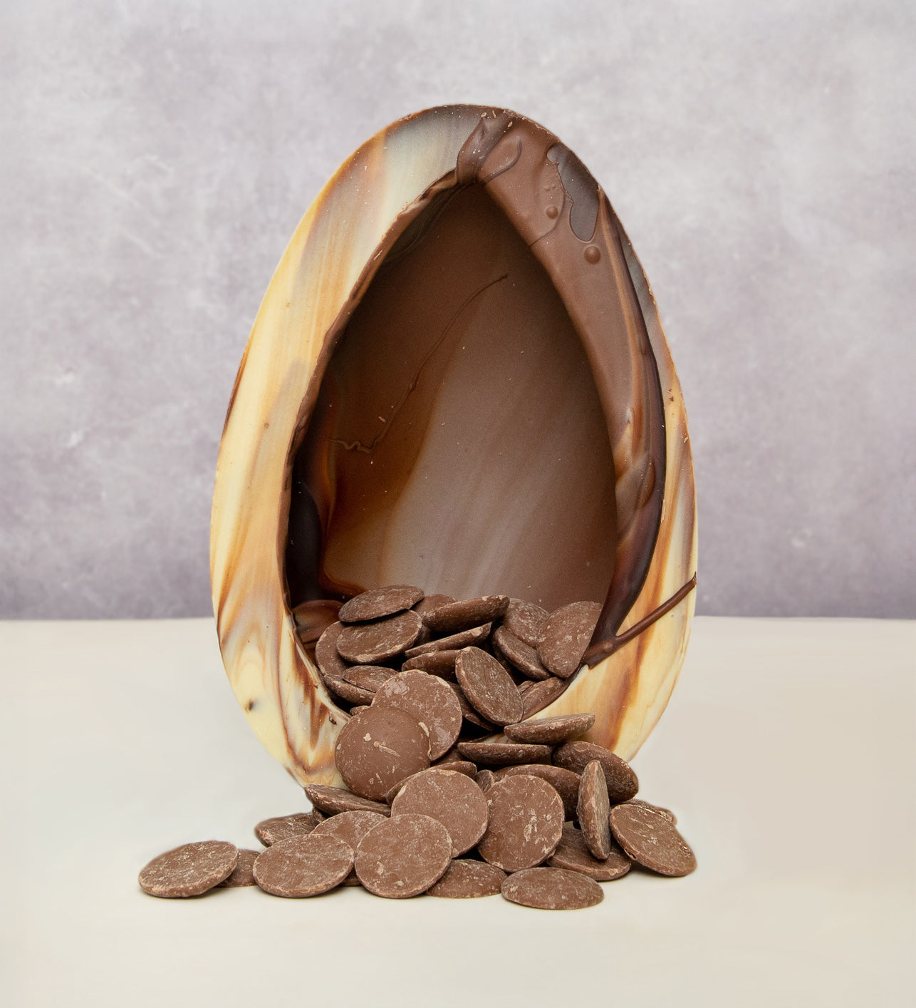 Cocoa Loco organic Fairtrade marbled Easter egg, handmade in the UK, halved to reveal milk chocolate buttons spilling from its centre.