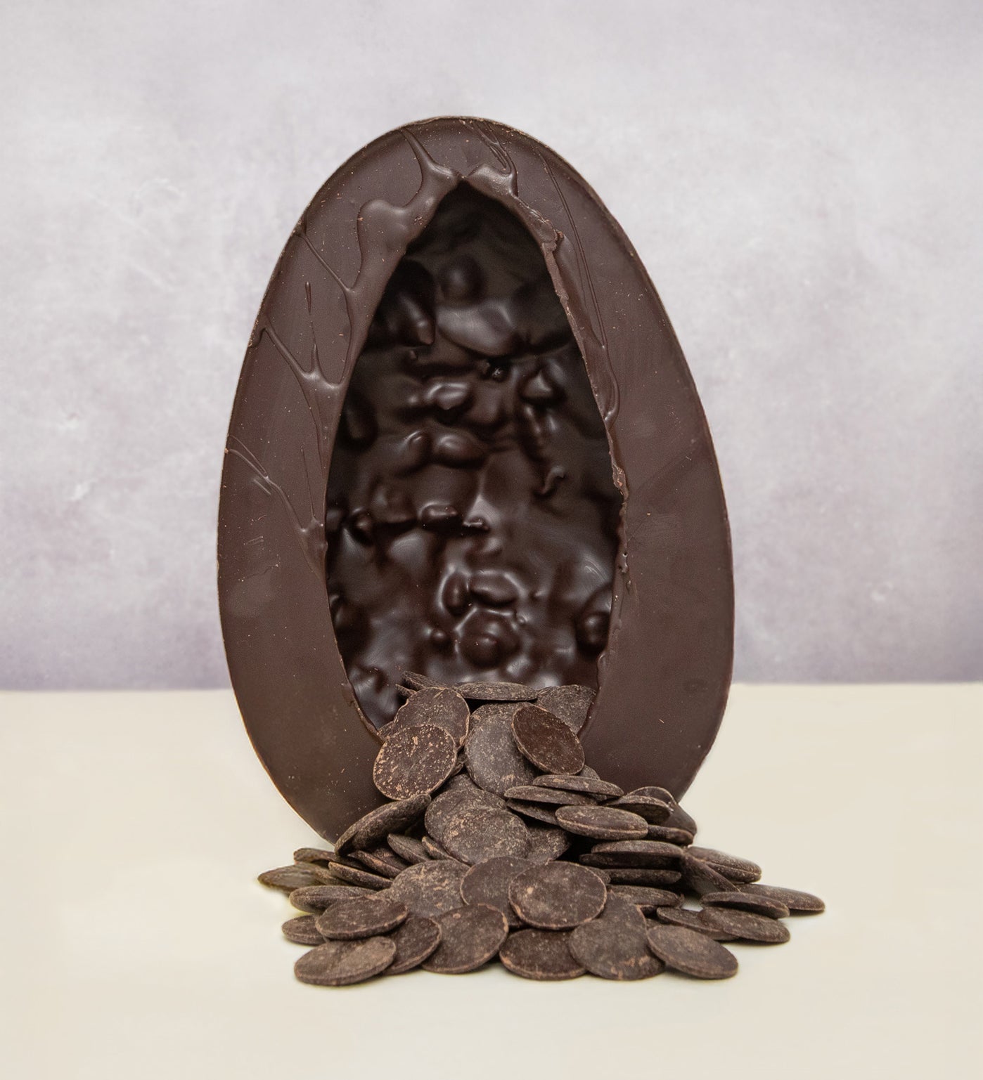 Cocoa Loco oragnic Fairtrade vegan dark chocolate easter egg, halved to reveal a cascade of dark chocolate buttons.