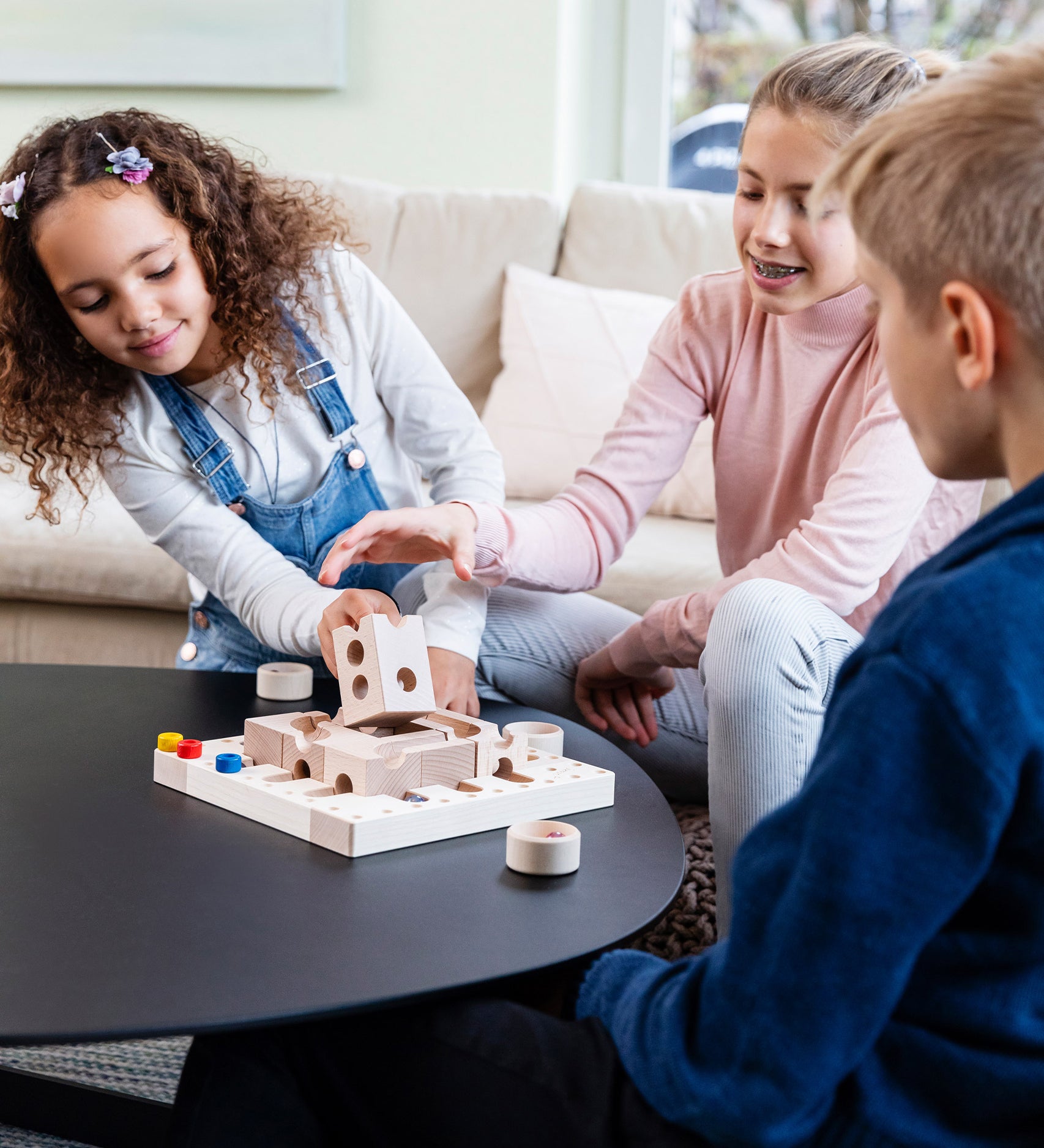 Three children playing with the Cuboro Tricky Ways Board Game on a black table