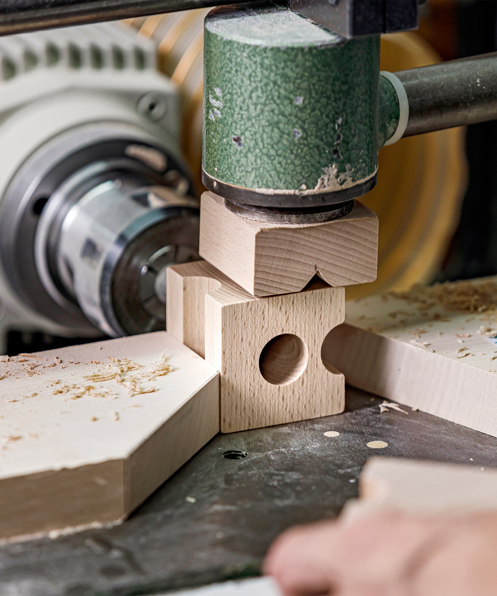 A closer look at the block creating process at Cuboro. The image shows a wooden block being cut into a marble run piece on a cutting machine