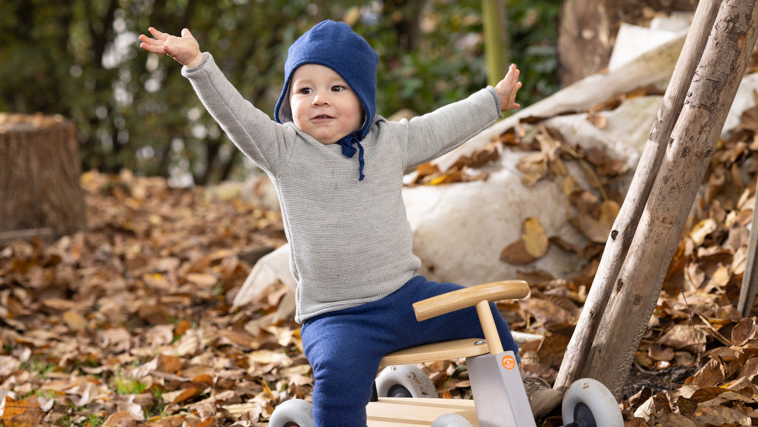 A small child wearing Disana organic baby clothing, playing in the forest.