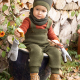 Disana organic merino wool dungarees worn by a toddler sitting on a plant pot