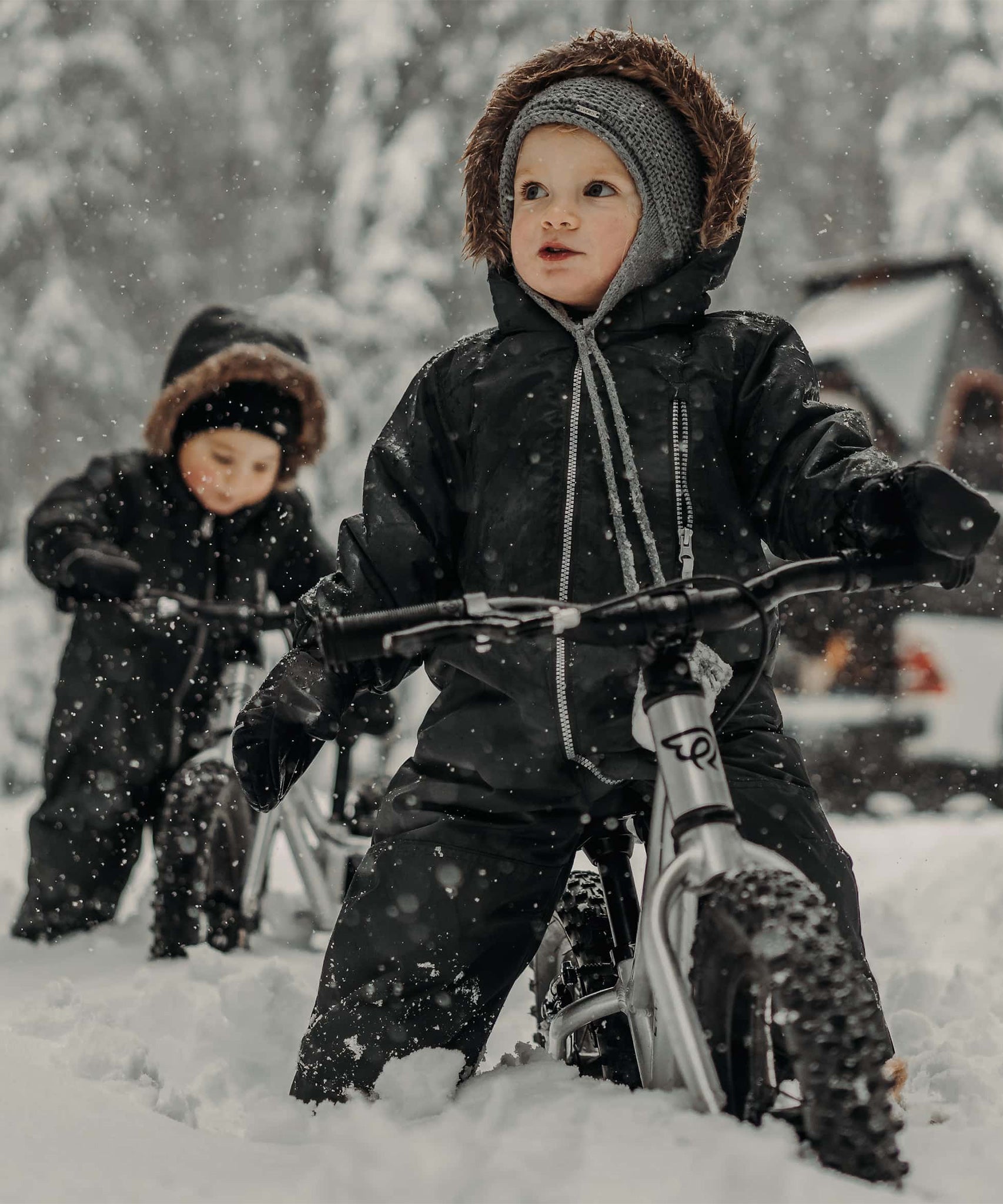 Two children playing in the snow on their Early Rider Big Foot Balance Bikes. The image shows how sturdy the Early Rider bikes are, and can be used in deep snow