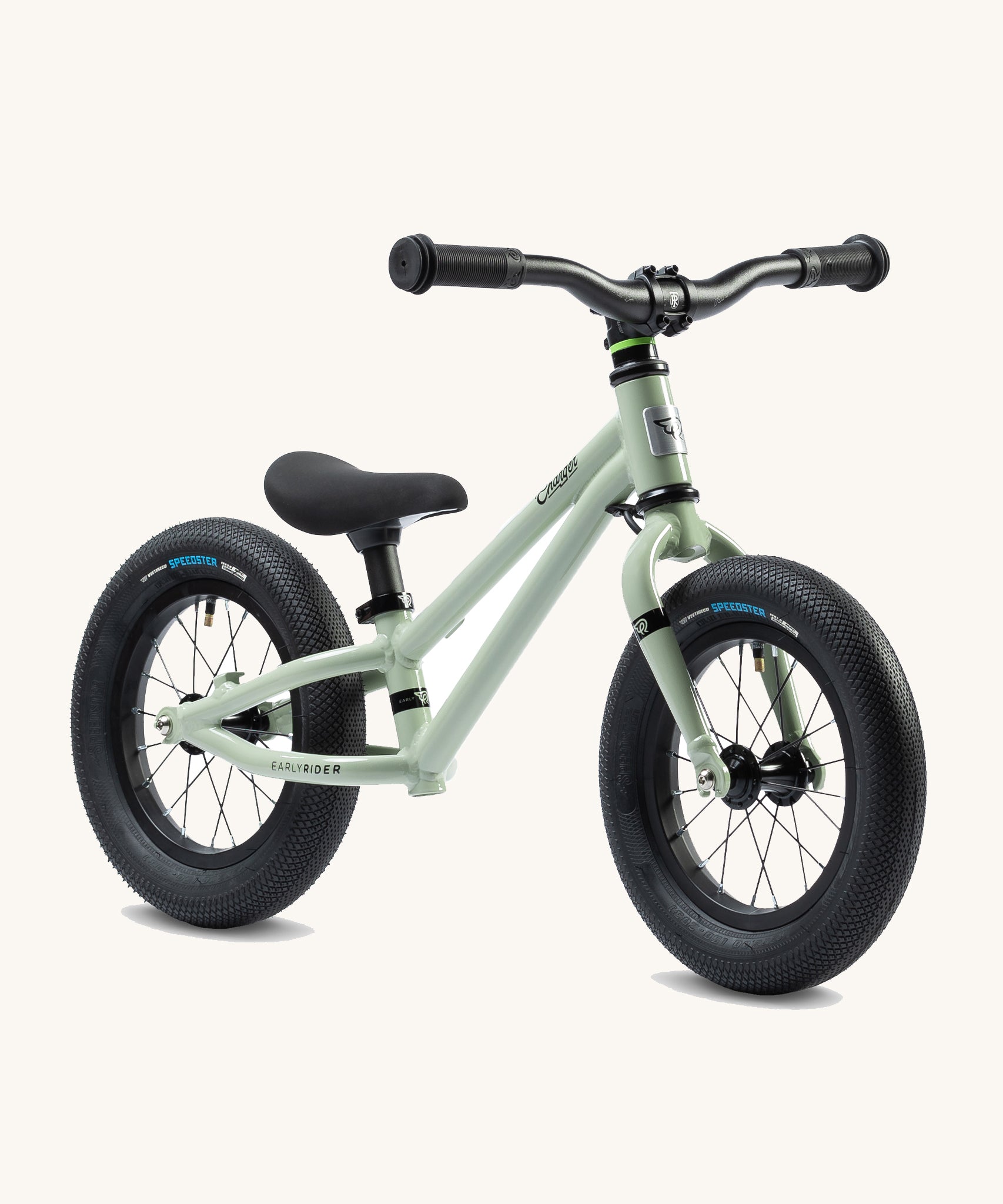 Early Rider Charger Balance Bike - Sage Green has a light sage green, low slung frame with chunky black wheels, a black seat and black handle bars. The bike is on a cream background