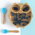 Eco Rascals Owl Bamboo Suction Plate with blackberries and blue berries and two blue silicone and bamboo baby spoons. 