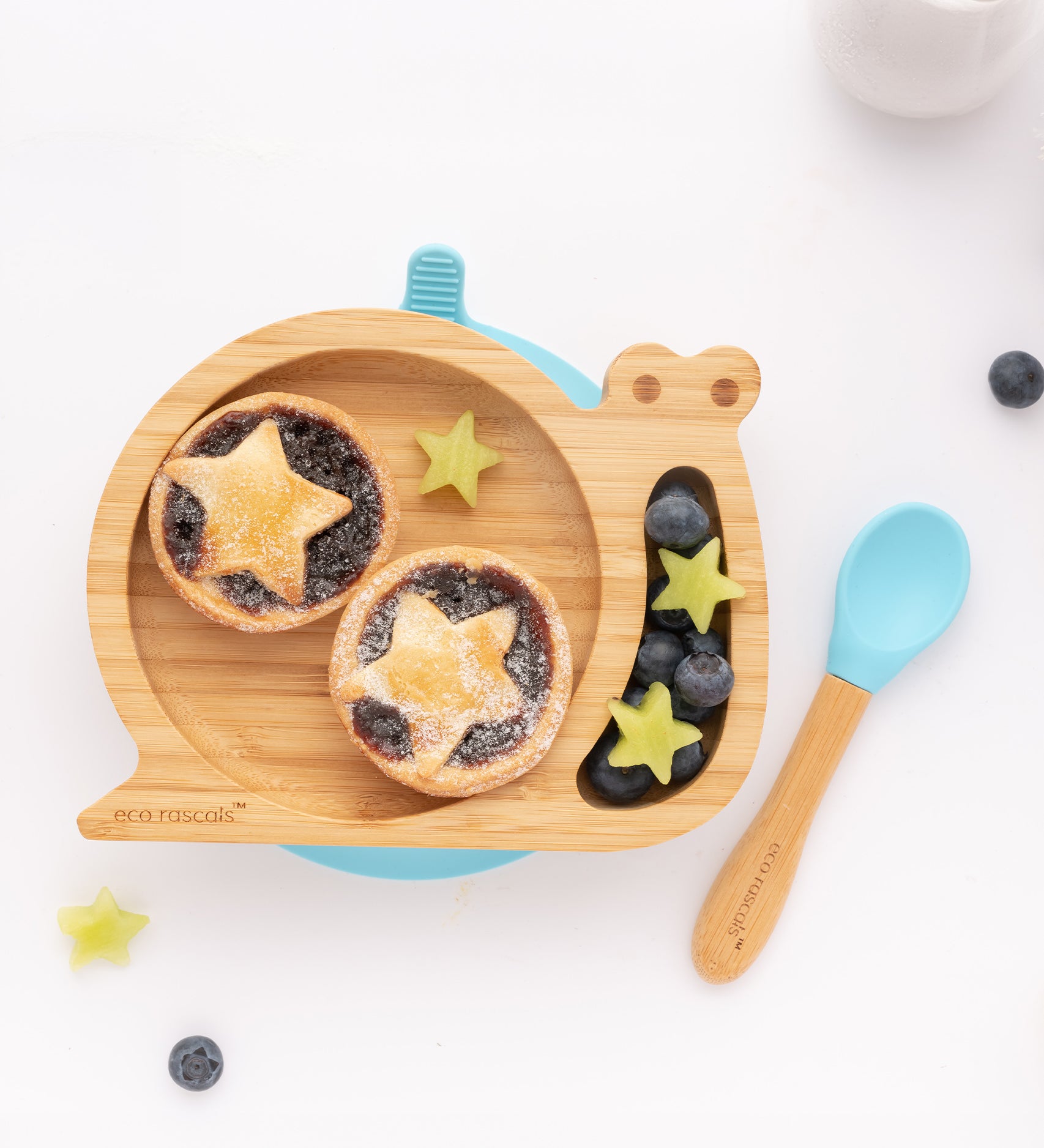 The Blue Eco Rascals Snail plate and spoon. The snail plate contains fruit tarts and various fruit 