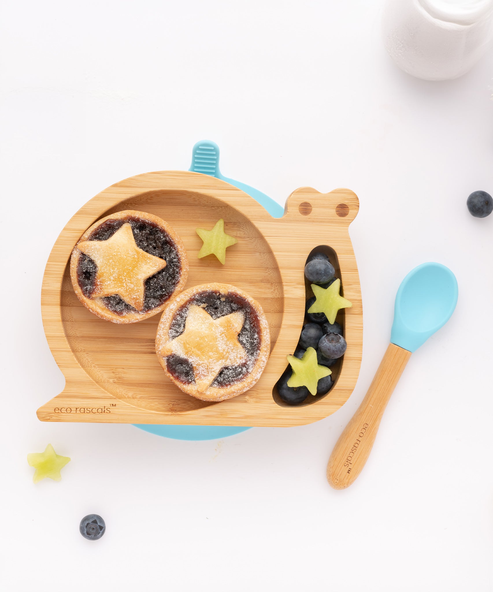 The Blue Eco Rascals Snail plate and spoon. The snail plate contains fruit tarts and various fruit 