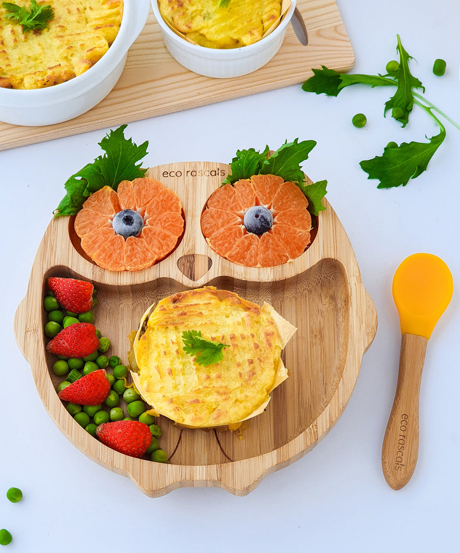 Eco Rascals Owl Bamboo Suction Plate with potatoe pie, peas and the owl eyes as orange segments, with and orange silicone and bamboo baby spoon.