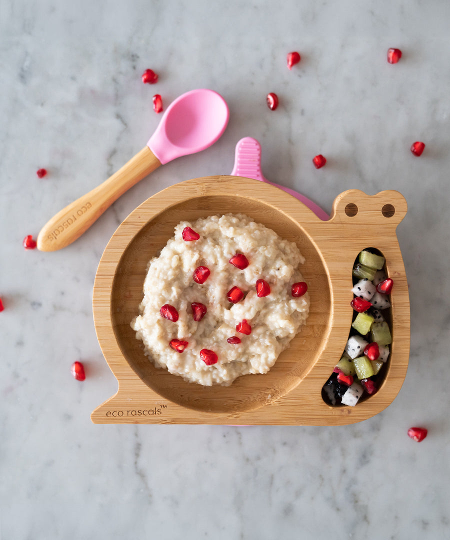 The Pink Eco Rascals snail plate and spoon, with various food in the plate compartments