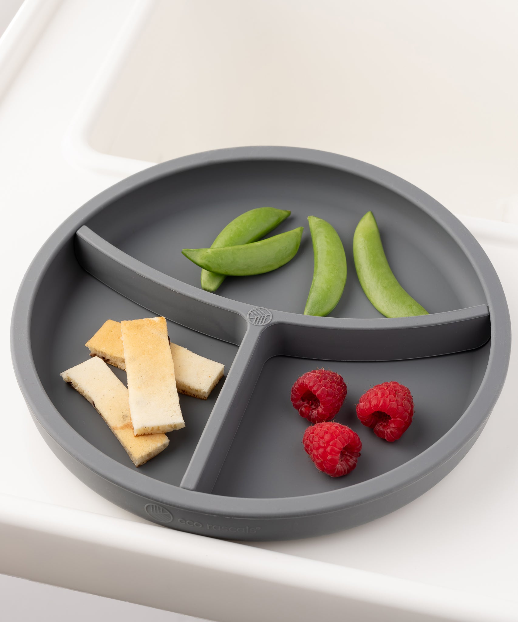 Eco Rascals Silicone Baby Plate in silver with removable divider, and cheese slices, raspberries and peas. 