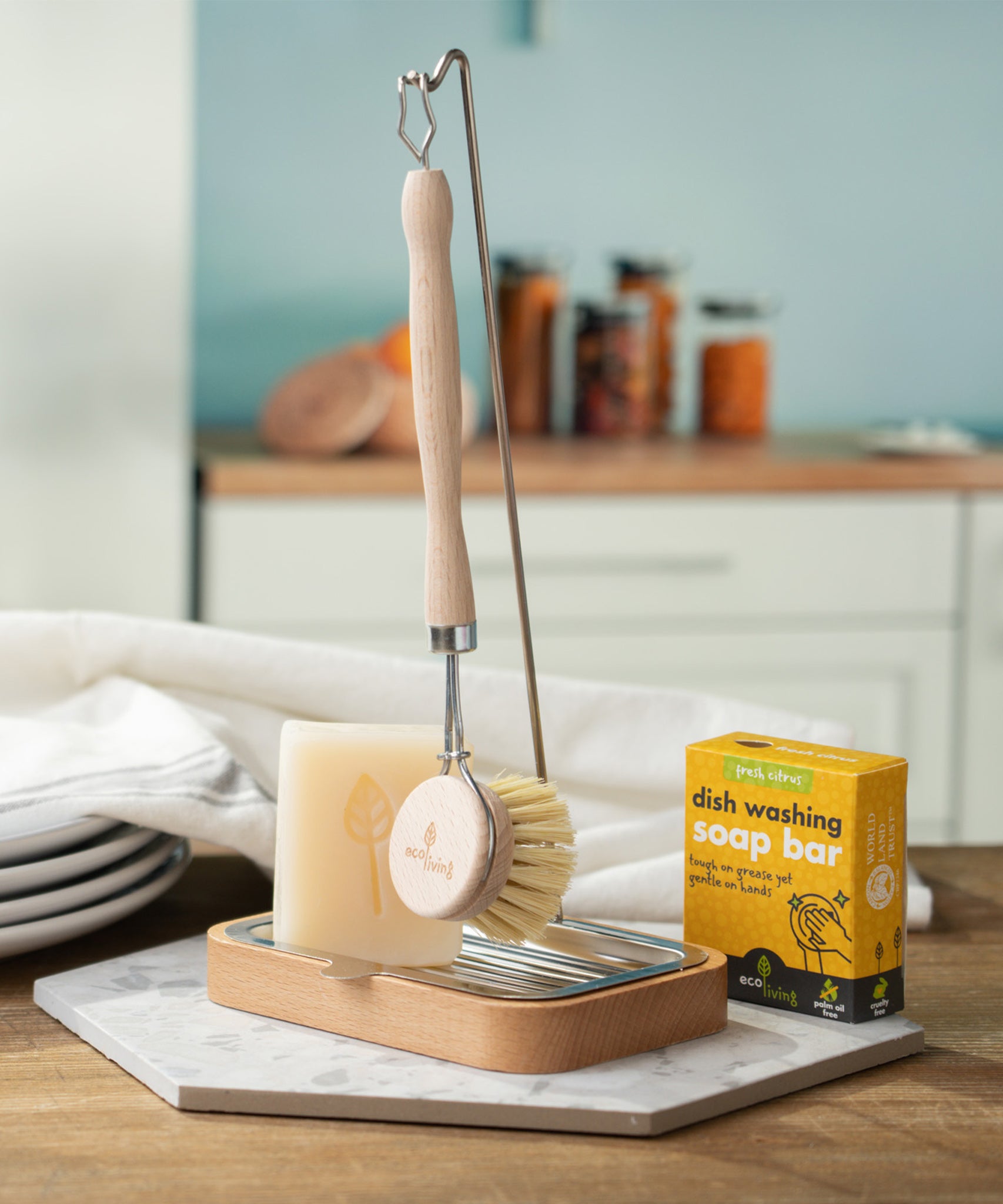 The Ecoliving dish brush holder with an Ecoliving dish soap bar in the soap tray, and an Ecoliving dish brush hanging from the metal hook n the thin pole