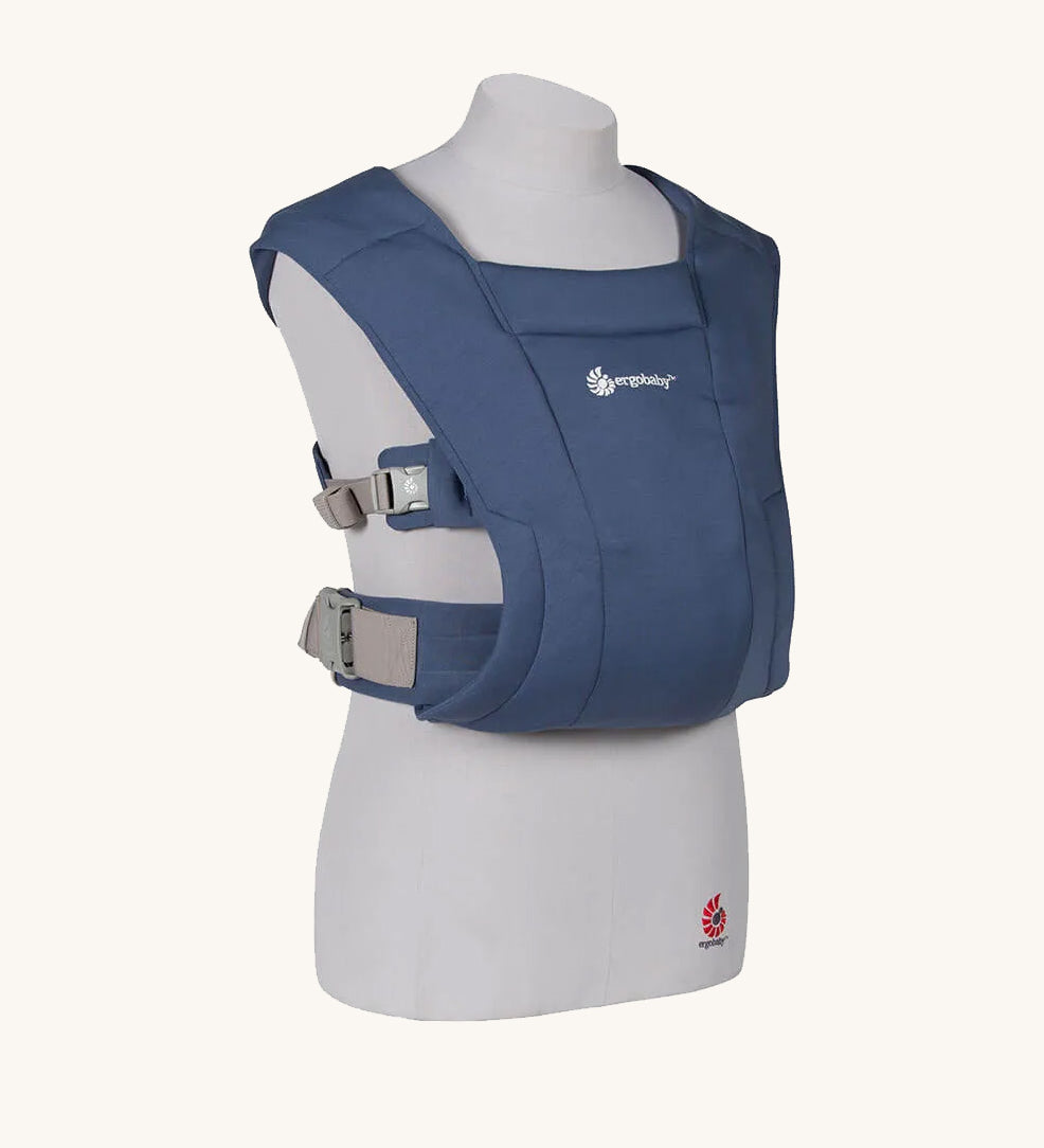 The Ergobaby Soft & Snug knit newborn baby carrier in a soft navy colour, from a side angle view.