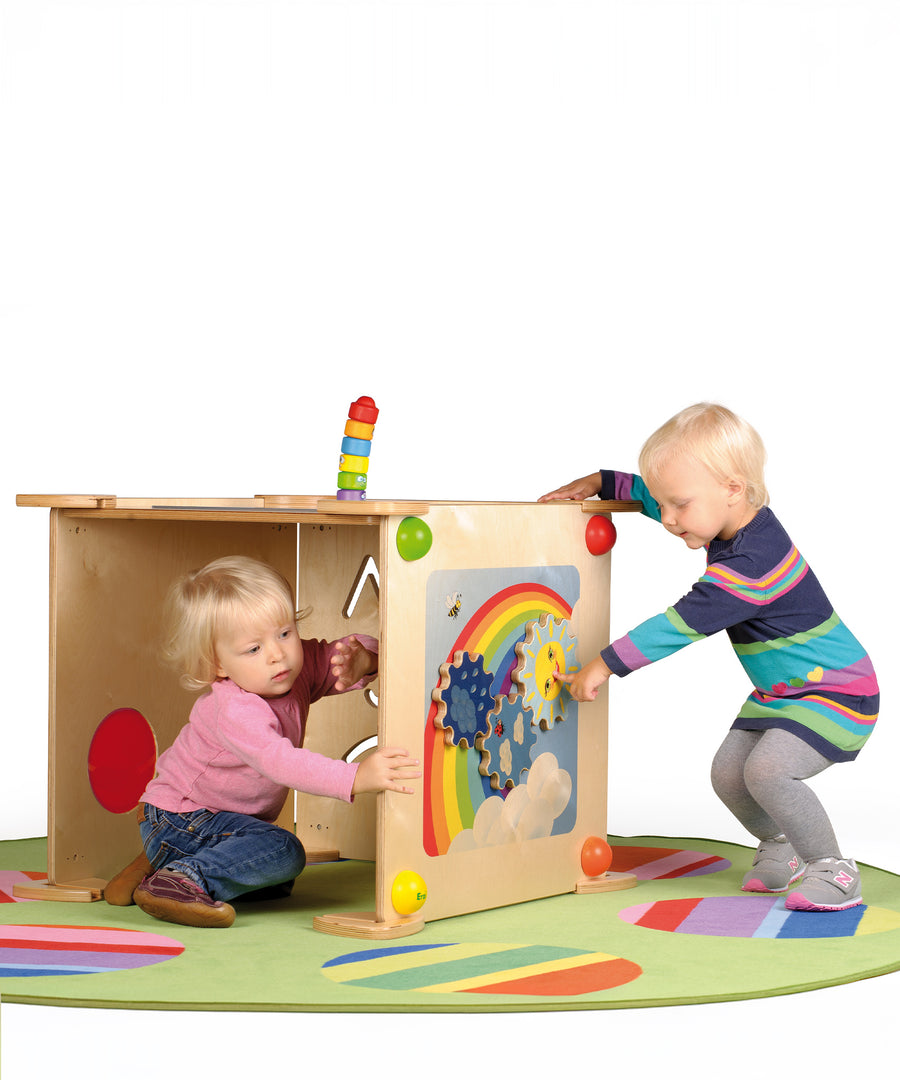 A child playing with the sun cog on the Erzi Sensory Weather Wall Board, with a child sat inside a sensory wall board den