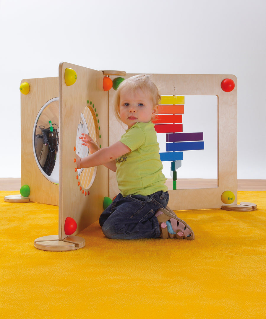 A child playing with the Erzi Baby Guitar Wall Board, which is connected to other Erzi Toy Wall Board activities