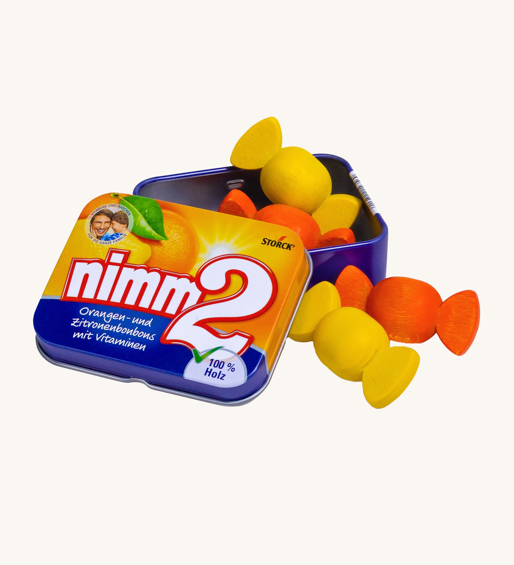 Erzi Wooden Nimm2 Bonbons In A Tin. Colourful wooden bonbon sweets which are orange and yellow, in a tin with a cream background