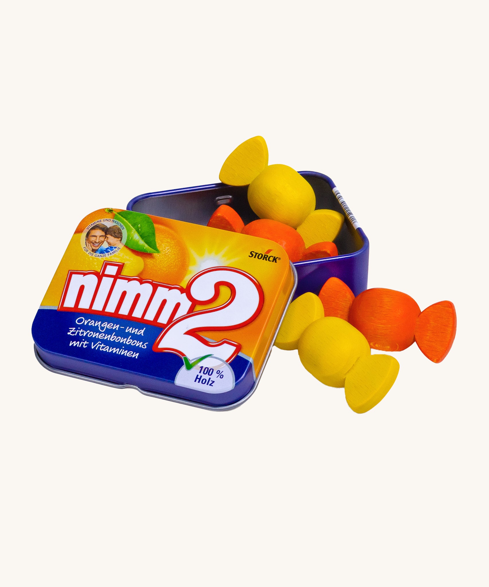 Erzi Wooden Nimm2 Bonbons In A Tin. Colourful wooden bonbon sweets which are orange and yellow, in a tin with a cream background