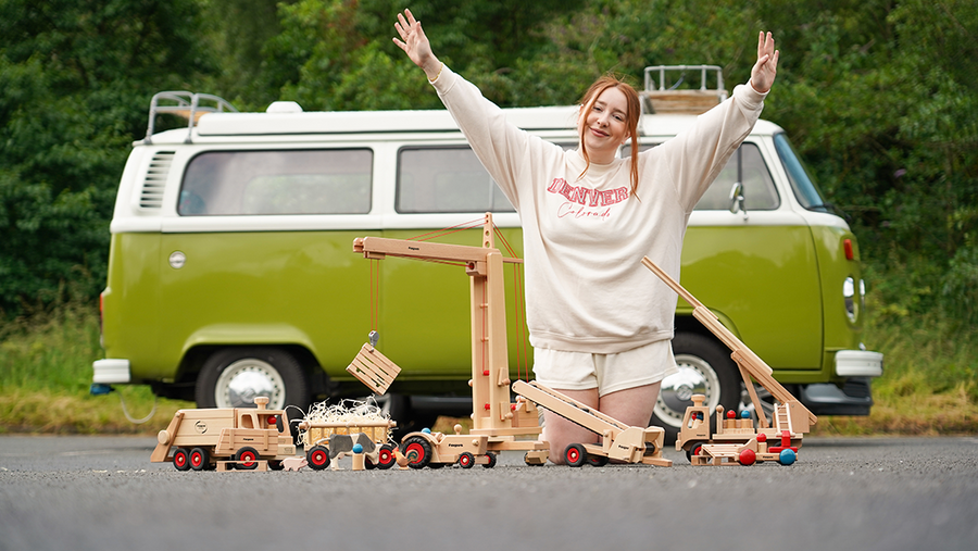 Charlotte playing with Fagus wooden toy vehicles, with a vintage camper van in the background