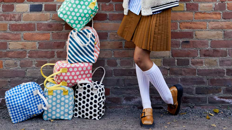 Picure of Fluf lunch boxes stacked on top of each other, next to a girl in school uniform.