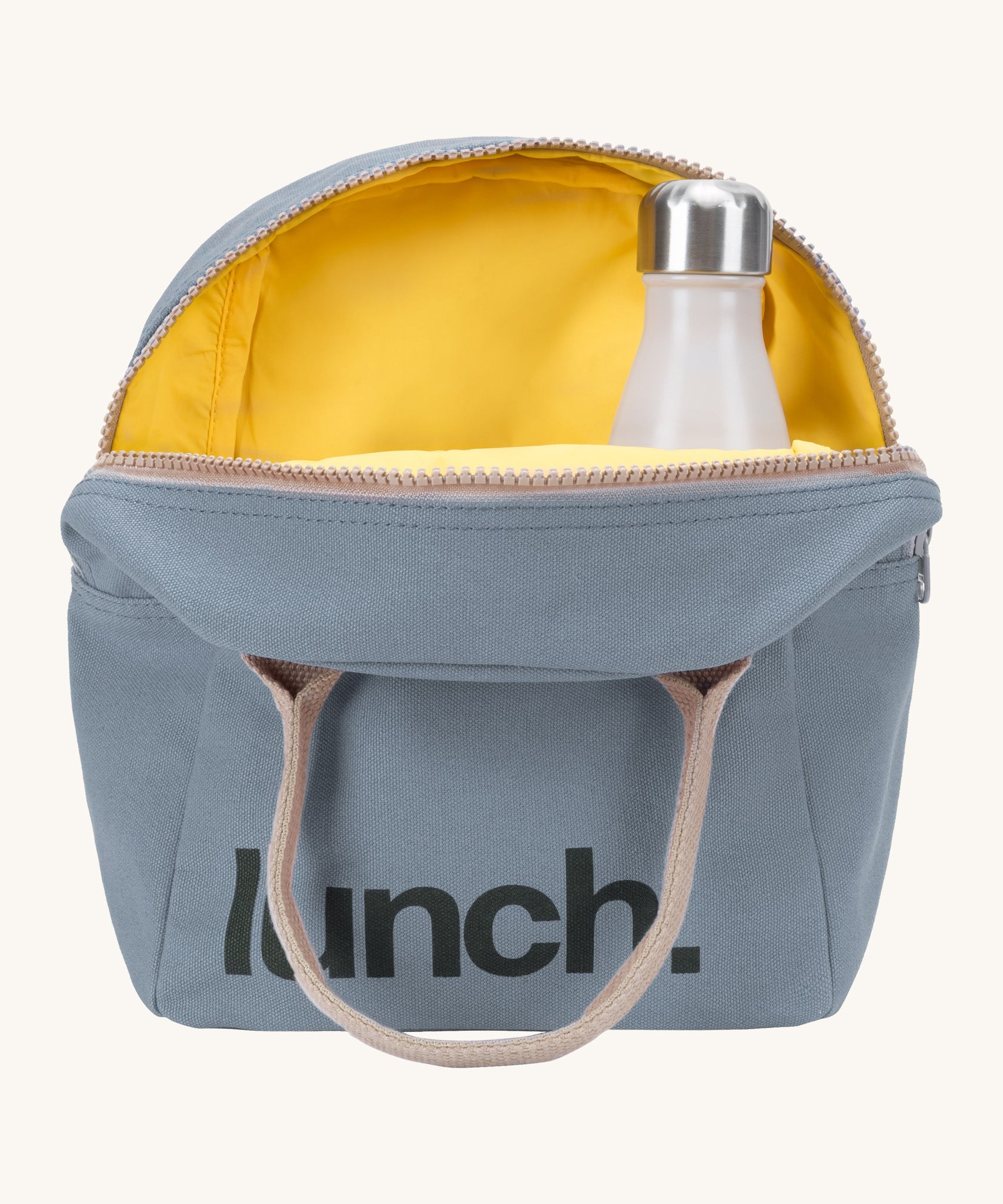 Fluf zip lunch bag in a light blue colour with a brown handle and a yellow inner lining holding a bottle on acream background.