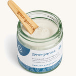 A opened jar of the English peppermint fluoride toothpaste with a wooden spatula dipped in.