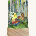 The Forest Whispers illustration by Eentje Van Margo sat in a Toverlux Magic Lantern base, on a cream background