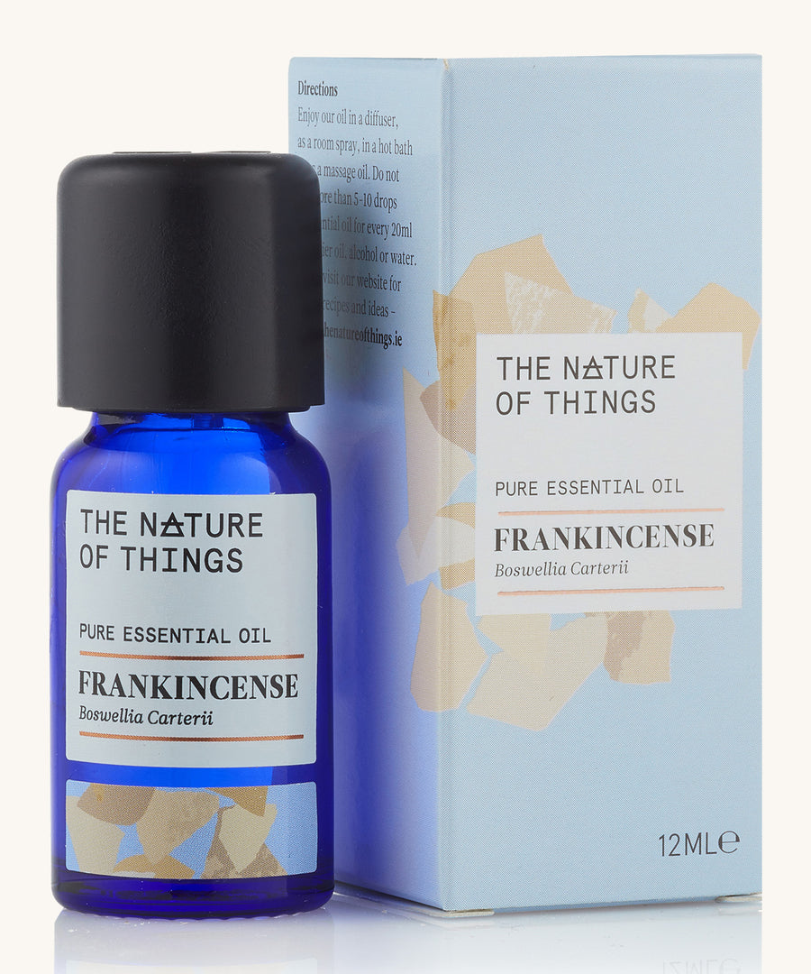 Frankincense pure essential oil in a blue glass bottle in front of a decorative blue cardboard box.