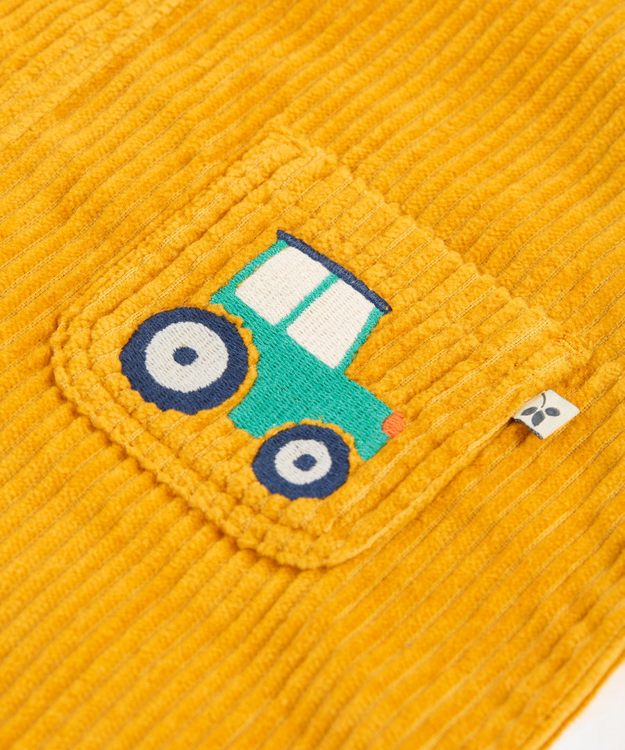 A closer look at the embroidered tractor on the pocket of the Frugi Adley Cord Dungarees - Gold/Tractor