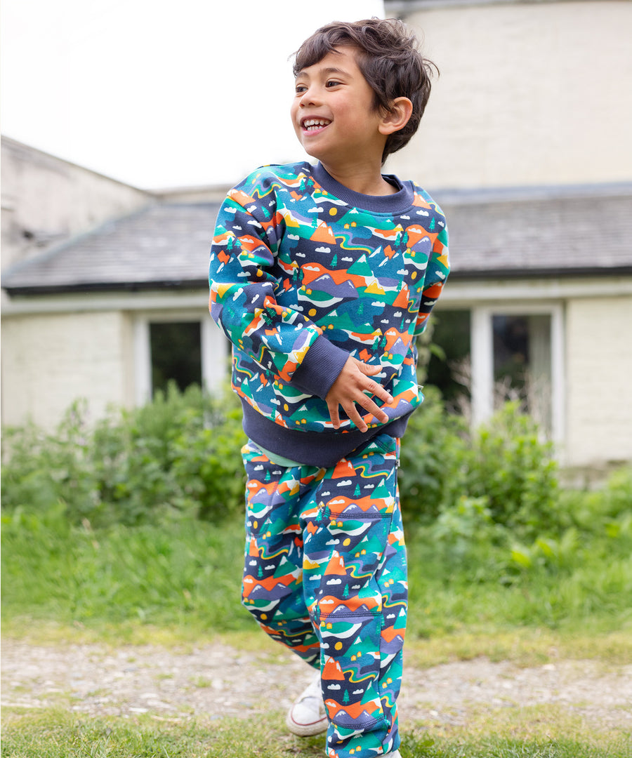 A child wearing the Frugi Malpas Joggers - Navy Alpine Adventures, and matching jumper