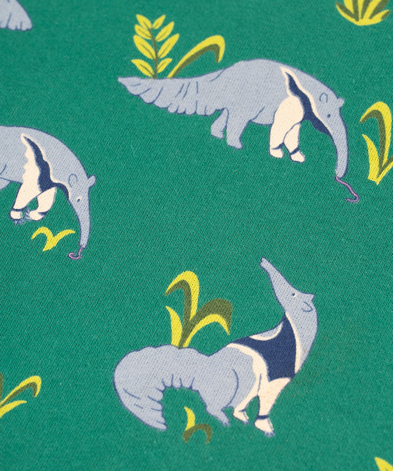 A closer look at the Anteater print on the Frugi Malpas Joggers - Anteater Parade. The image also shows green plant/leaf details next to the anteaters