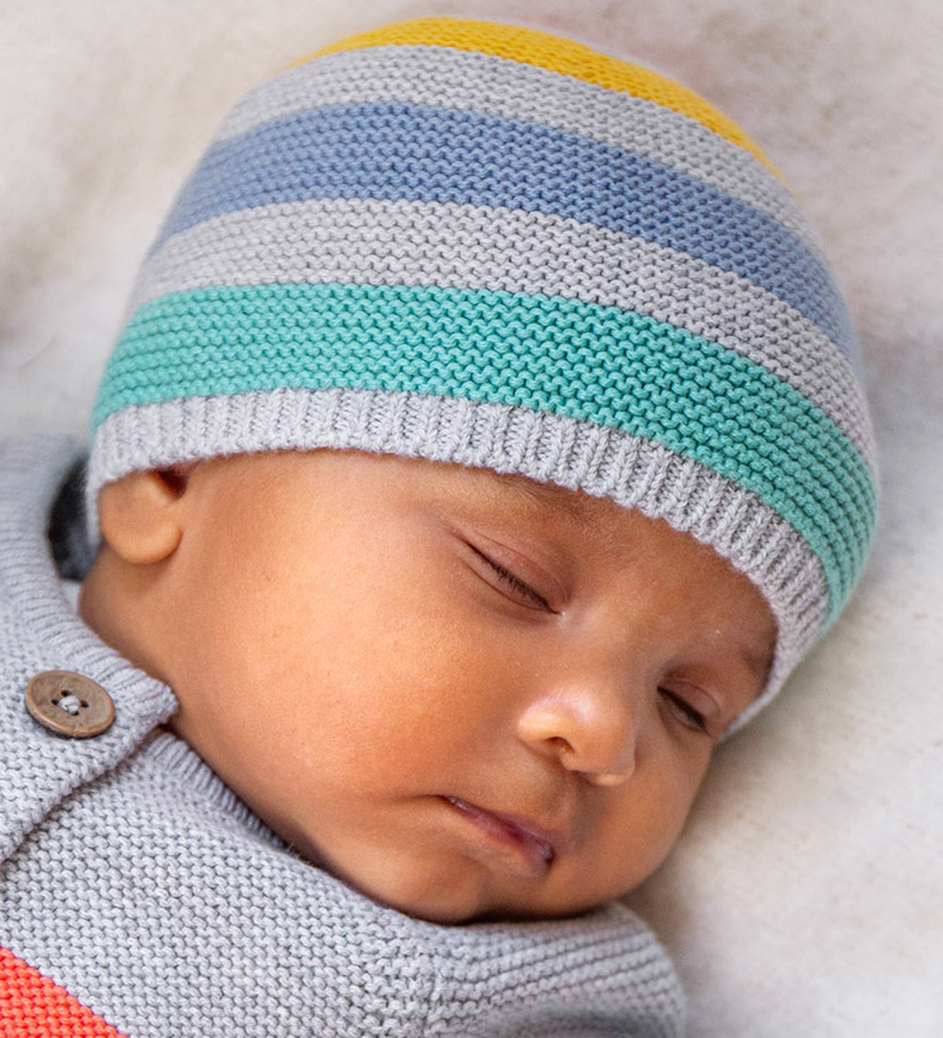 A baby wearing the Frugi Harlen Knitted Hat - Grey Marl Stripe