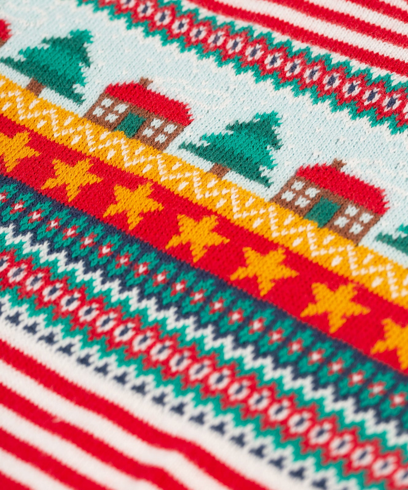 A closer look at the Christmas tree, house and star print on the chest of the Frugi Lumi Knitted Romper - Fairisle Christmas Stripe