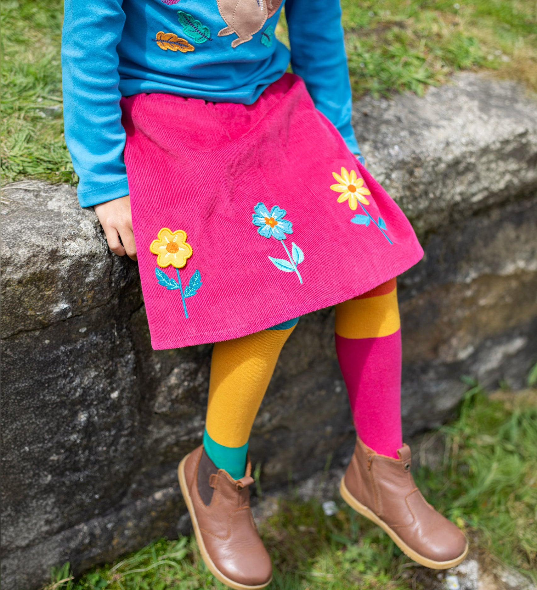 A child wearing the Frugi Norah Tights - Deep Water Colour Block with a Frugi skirt and top